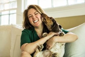 Woman hugging a foster dog on her couch in her home.