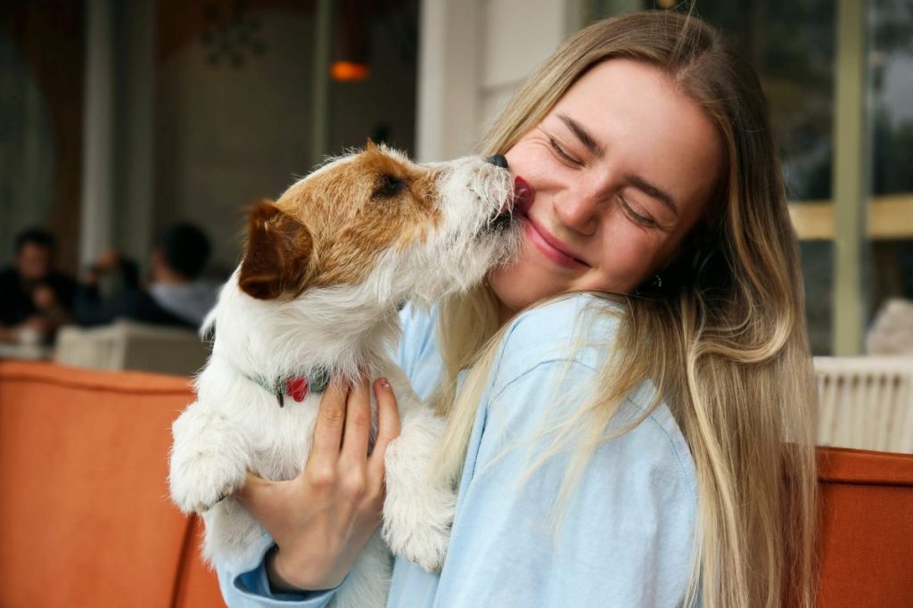 Dog licking woman’s face. A dog breath freshener can help keep your pup’s mouth healthy and ensure better interactions with them.